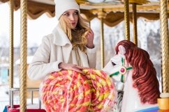 A blonde girl is standing on a carousel with two lollipops Product Image 2