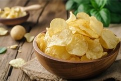 Bowl of crispy golden potato chips on wooden table Product Image 1