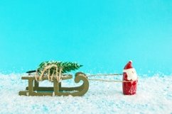 Santa Claus is carrying a Christmas tree on wooden sleigh. Product Image 1