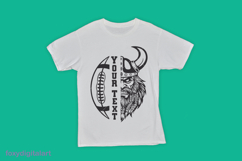 The image shows a white t-shirt featuring a bold Viking football graphic. The design is split vertically: on the left, a football with the text "YOUR TEXT" in large, bold letters; on the right, a Viking face with a helmet and a detailed beard. The t-shirt