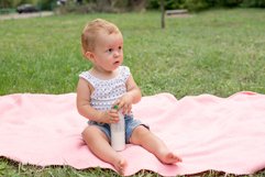 Baby holding bottle with milk or kefir, kid in the park Product Image 1