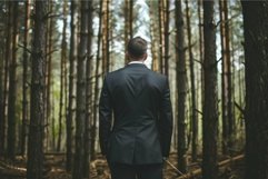 Rear view of a man in a suit standing thoughtfully amidst ta Product Image 1