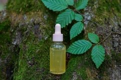 Dropper glass bottle with cosmetic oil or serum on nature Product Image 1