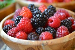 Fresh raspberries and blackberries in wooden bowl Product Image 1