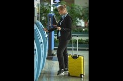 A young fair haired woman in an airport near the self check Product Image 1