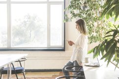 A girl in a white shirt is looking at smartphone. Product Image 1