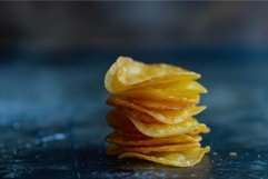 Stack of crispy potato chips standing on dark blue surface Product Image 1