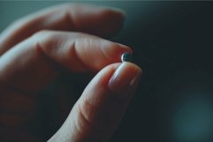 Closeup of hand holding tiny object Product Image 1