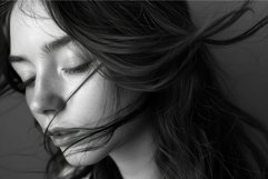 Close-up of a serene woman with windswept hair in black and Product Image 1