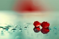 Two red berries laying on a wet surface reflecting on the wa Product Image 1
