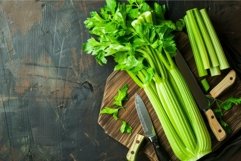 Bunch of fresh celery lying on wooden cutting board Product Image 1