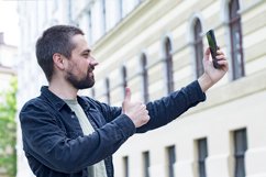 Caucasian blogger halds phone, smiles and likes. Product Image 1