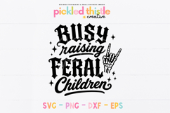 Black and white SVG design reading Busy Raising Feral Children in gothic and script lettering with sparkles and skeleton rock hand illustration