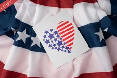 The patriotic cut file is depicted on a sheet of white paper lying on the flag of America. Heart in the color of the American flag