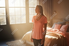 Woman standing in sunlit bedroom peach t-shirt Product Image 1