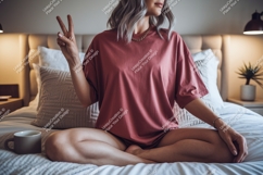 Woman peace sign seated on bed wearing pink t shirt Product Image 1