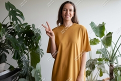 Woman wearing yellow t shirt making peace sign image Product Image 1