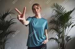 Woman showing peace sign wearing teal t-shirt image Product Image 1