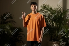 Young man orange shirt peace sign plants image Product Image 1