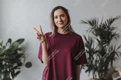 Woman wearing maroon t shirt making peace sign image Product Image 1