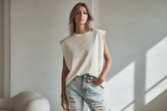 Woman wearing cream sleeveless top light wash ripped jeans Product Image 1