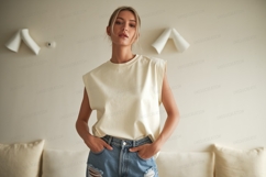 Woman wearing cream sleeveless top and ripped jeans Product Image 1