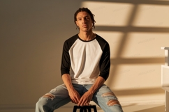 Man wearing baseball shirt and ripped jeans image Product Image 1