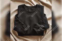 Folded Black Sweatshirt On Textured Beige Background Product Image 1