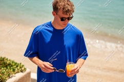 Man holding drink sunglasses beach ocean Product Image 1