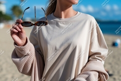 Woman holding sunglasses at beach sand Product Image 1