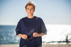 Woman dark blue shirt holding sunglasses beach image Product Image 1