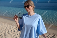 Woman wearing blue shirt and sunglasses on beach image Product Image 1