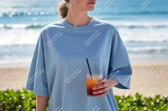 Woman wearing blue shirt holding drink beach Product Image 1
