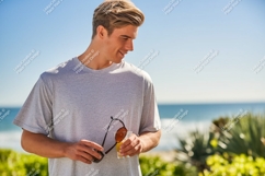 Man holding sunglasses and drink beach ocean Product Image 1