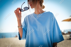 Woman holding sunglasses blue shirt beach image Product Image 1