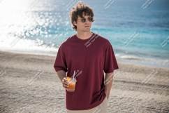 Man holding drink on sandy beach maroon t-shirt Product Image 1