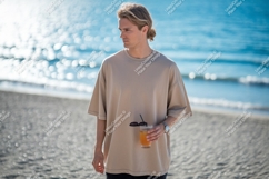 Man wearing beige t shirt holding drink beach ocean Product Image 1
