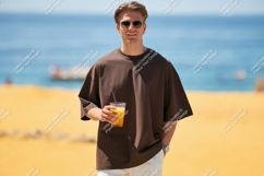 Man holding orange drink on beach ocean summer Product Image 1