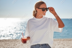 Woman holding drink sunglasses beach ocean Product Image 1