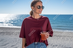 Woman wearing maroon t shirt holding drink on beach Product Image 1