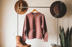Dusty rose sweatshirt hanging on rack with hats and boots Product Image 1