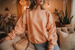 Woman in peach sweatshirt on couch mockup Product Image 1