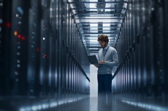 Man in Server Room Working on Laptop with Data Center Racks Product Image 1