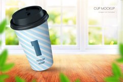 Realistic paper coffee cup mockup in bright room with big window