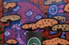 reusable-cup-mockup-featuring-a-colorful-wall-with camp print sticker design