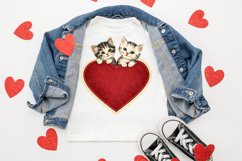 Romantic cat clipart featuring two kittens with green and blue eyes resting on a red heart trimmed with delicate lace edging.