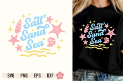 Model wearing a black t-shirt printed with a retro pastel graphic reading "Salt Sand Sea"