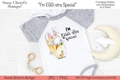 An adorable baby Easter bunny, holding a carrot in a cracked yellow Easter egg clipart. Sentiment reads, I'm EGG-stra special. Shown on a baby onesie.