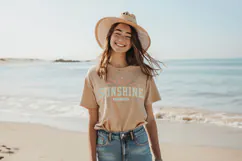 Beach-inspired shirt design featuring bold collegiate font and sun graphic, soft pastel tones and worn texture for a relaxed summer look