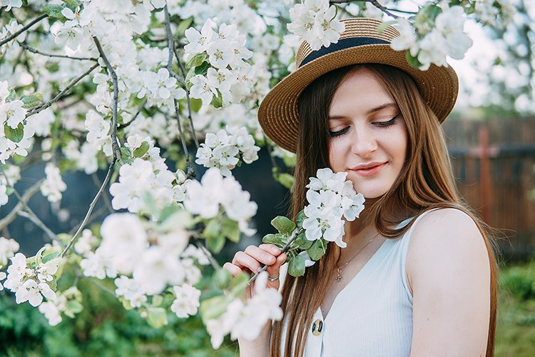 Beautiful young girl in hat in blooming Apple orchard.